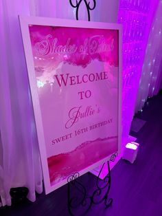 a welcome sign is lit up with purple lights at the entrance to a pink themed birthday party