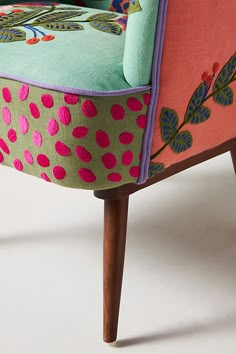 an upholstered chair with pink, green and blue fabric on the armrests