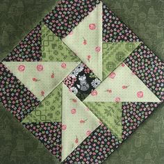 a green and pink patchwork quilt with flowers on the top, which has been made into a square