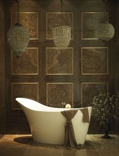 a bathtub in the middle of a room with chandeliers hanging above it