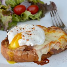 a piece of bread topped with an egg and cheese on it next to a salad