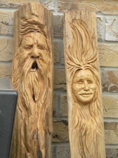 two carved wood faces are next to each other on a brick wall with a speaker in the foreground