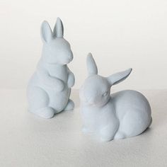 two white ceramic rabbits sitting next to each other