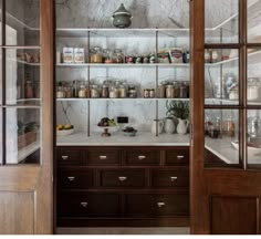 an open pantry with glass doors and shelves filled with various items on the counter top