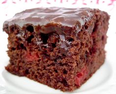 a close up of a piece of cake on a plate with chocolate frosting and cherries