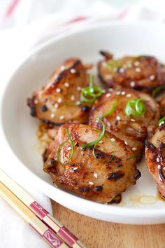 a white plate topped with meat covered in sesame seeds and garnished with green onions