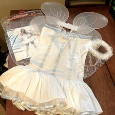 a white dress and headband are sitting on a wooden table next to an album