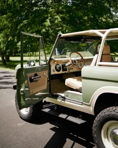 an old jeep is parked on the side of the road in front of some trees