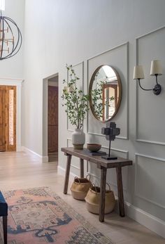 a living room filled with furniture and a round mirror on the wall above a wooden table