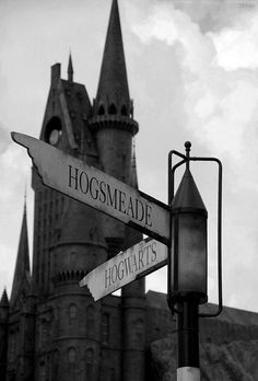 black and white photograph of hogwart's castle with street sign in foreground