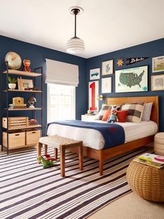 a bedroom with blue walls and pictures on the wall above the bed, along with a striped rug