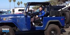 a man sitting in the driver's seat of a blue jeep