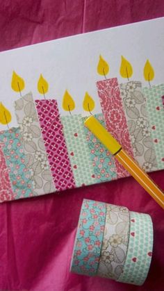 a birthday card with candles on it next to a roll of tape and a pencil