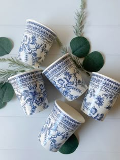 six blue and white cups sitting on top of each other next to some green leaves