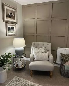 a living room with a chair, lamp and pictures on the wall in it's corner