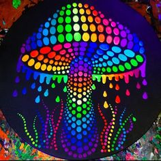 a colorful painting on a black surface with drops of paint coming out of the top