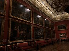 an empty room with many paintings on the wall and chairs lined up in front of it