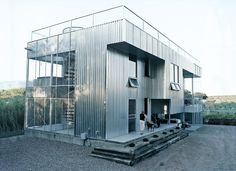 a woman and her dog are standing in front of a metal building that is made out of corrugated