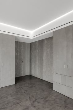 an empty room with concrete walls and flooring is lit by recessed lighting on the ceiling