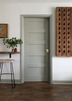 an open door in a white room next to a table with a potted plant on it