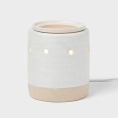 a white and beige ceramic jar with lights on the inside, sitting on a table