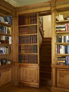 an open bookcase with many books on it and stairs leading up to the second floor