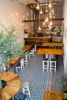 an empty restaurant with wooden tables and white chairs, lights hanging from the ceiling above