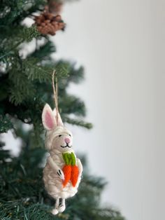 an ornament shaped like a bunny holding a carrot hanging from a christmas tree