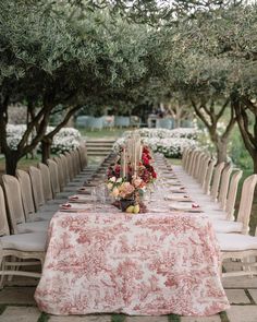 a long table is set up with white chairs and pink linens for an outdoor dinner