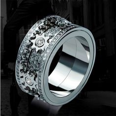 a silver ring with gears and diamonds on the inside, in front of a black background