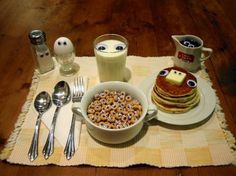 a table topped with pancakes and cereal on top of a white plate next to two glasses of milk