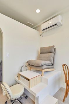 an air conditioner sitting on top of a white shelf next to a chair and desk