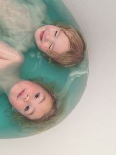 three children are swimming in a blue tub