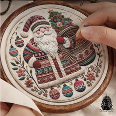 someone is stitching a christmas ornament on a piece of wood