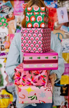 a woman is holding several colorful boxes in her hands