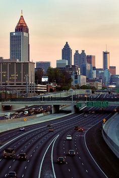 a freeway with lots of traffic and tall buildings in the background