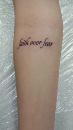 a tattoo that reads faith over fear on the side of a woman's leg