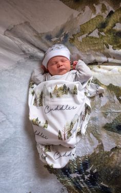 a baby wrapped up in a blanket with trees on it