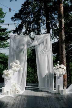 an outdoor wedding setup with white flowers and drapes