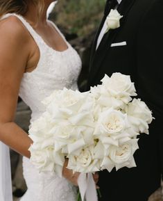 the bride and groom are posing together for a wedding photo with white flowers in their bouquet