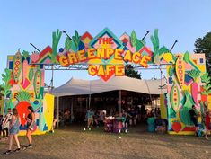 people are standing under the greenpeace cafe sign at an outdoor event in front of a tent