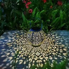 a blue vase sitting on top of a tiled floor next to green plants and flowers