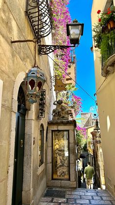 an alleyway with lanterns and flowers on the side