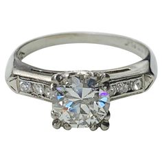 an antique style diamond engagement ring with channeled shoulders and round brilliant cut diamonds on the sides