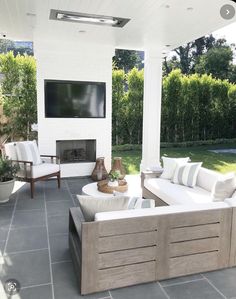 an outdoor living area with white furniture and a flat screen tv mounted on the wall