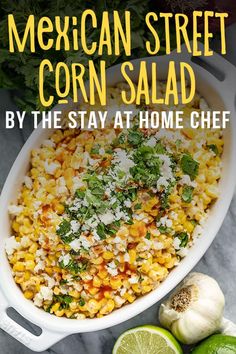 mexican street corn salad in a white dish with limes and cilantro on the side