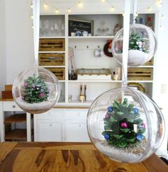 two glass ornaments hanging from the ceiling in front of a book shelf with christmas decorations on it