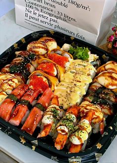 an assortment of different types of sushi in a black platter on a table