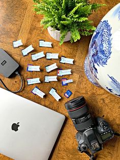 a laptop computer sitting on top of a wooden table next to a camera and other items