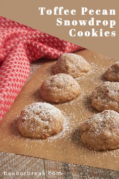 several powdered sugar cookies sitting on top of a cookie sheet with the words toffe pecan snowdrop cookies